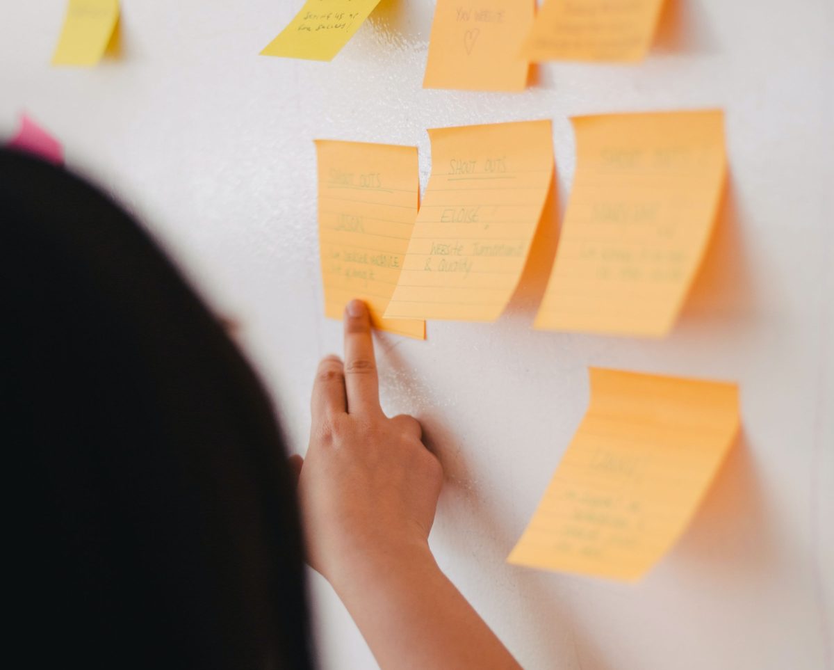 A shot from behind of someone putting post it notes on a wall