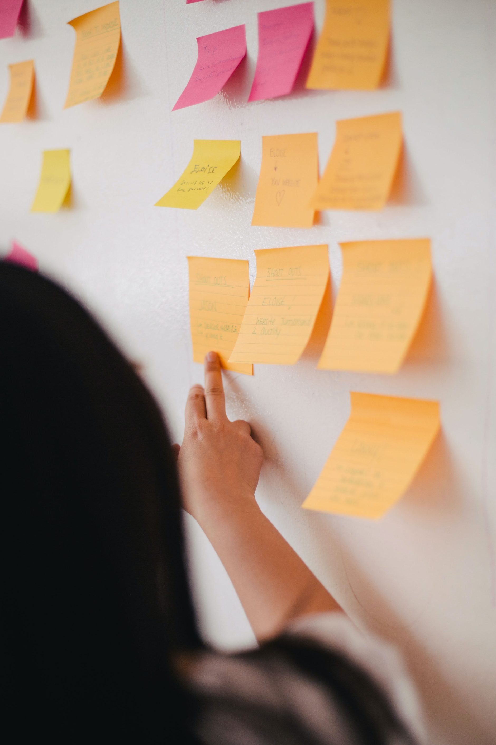 A shot from behind of someone putting post it notes on a wall