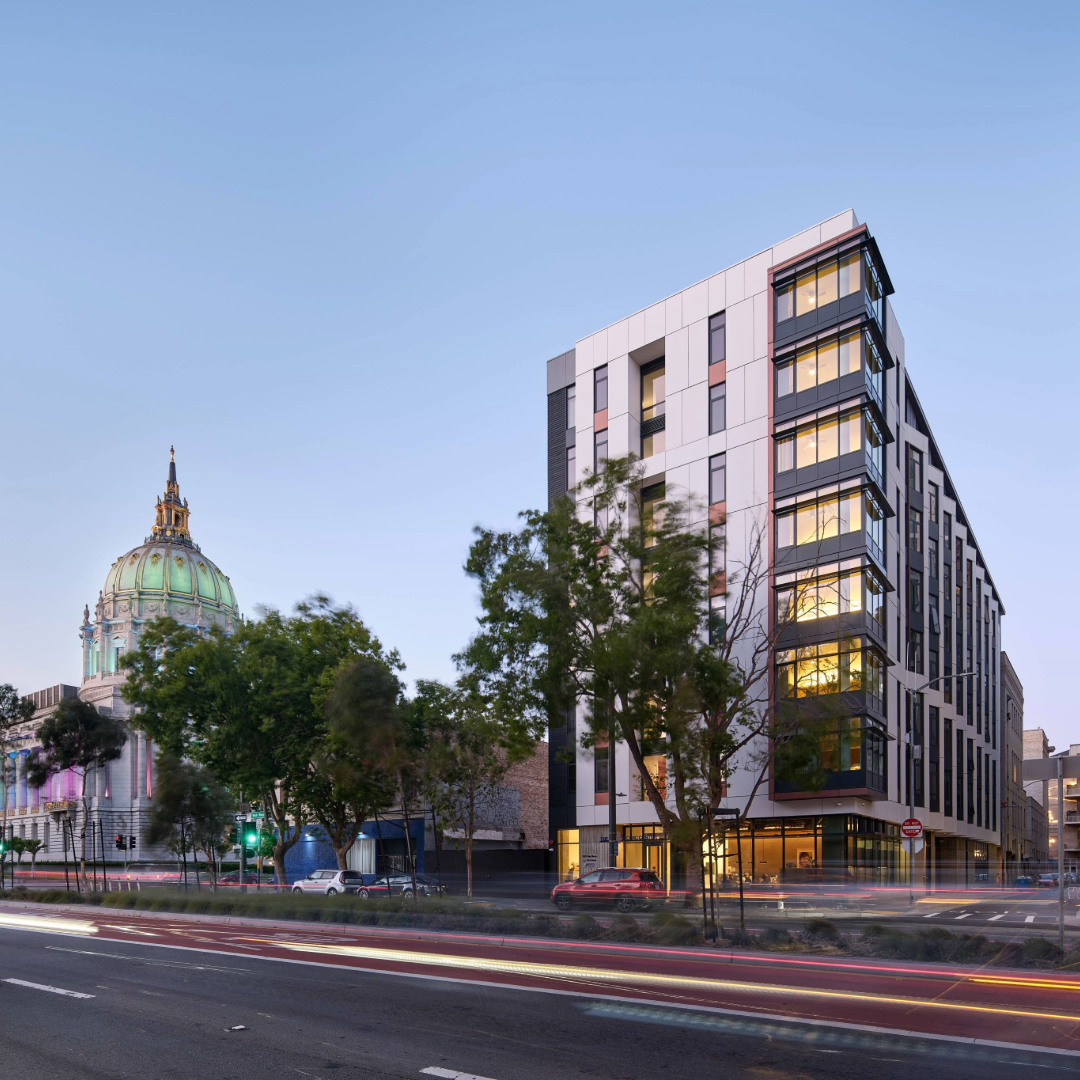The Kelsey Civic Center is visible with a blue sky in the background. San Francisco City Hall is visible behind the building.