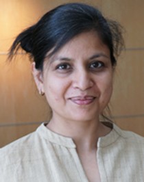 image of Vinita, a person of color with hair up smiling at camera wearing a tan shirt.