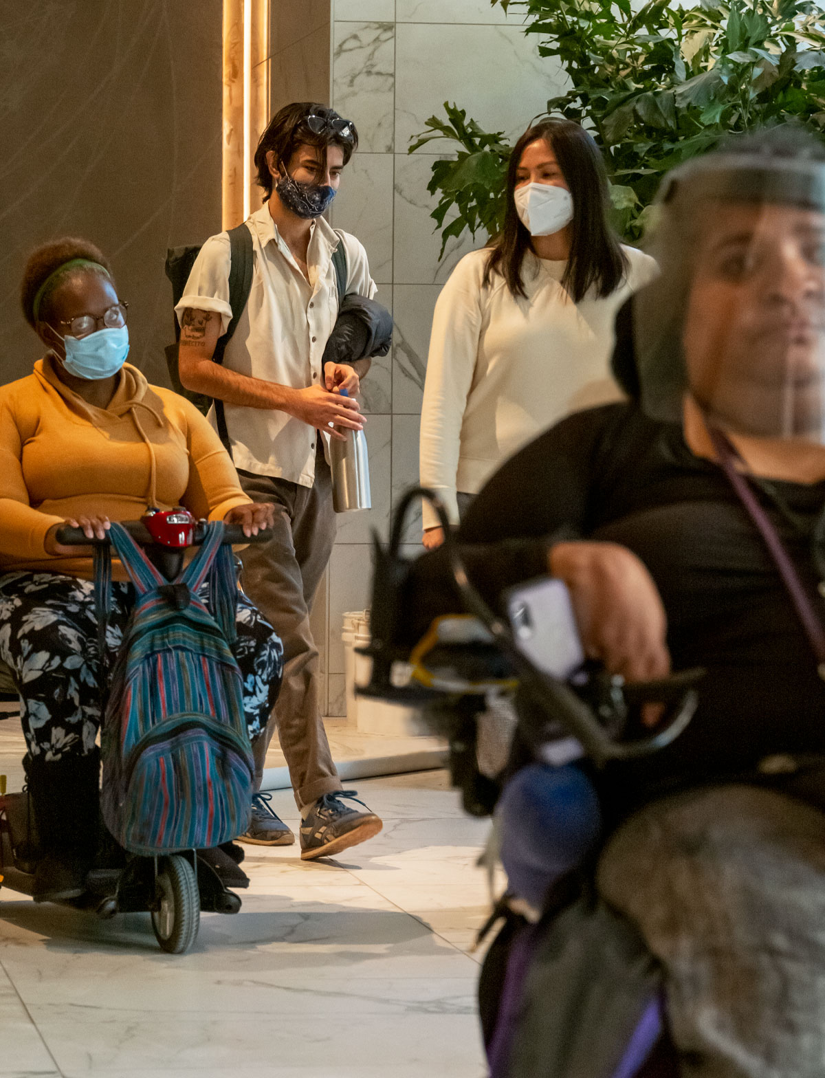 A group of people walk and wheel through the lobby of Atlas. They are all wearing masks.