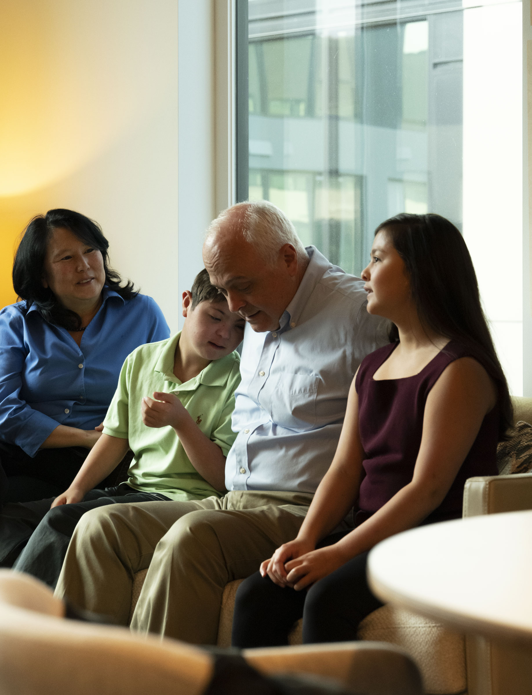 A young boy with a disability and a young girl sit with and older man and woman.