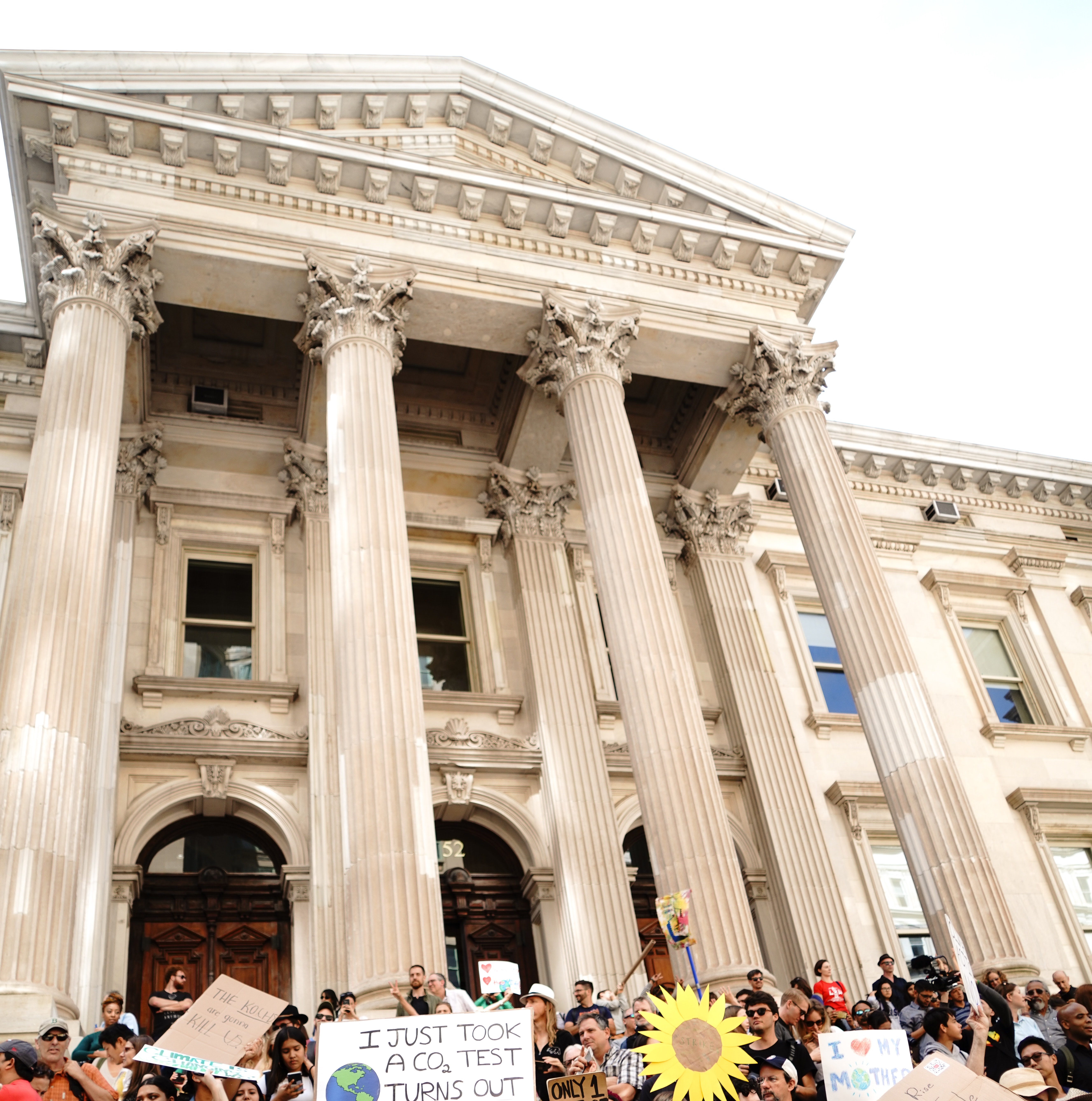 Image of a government building with people and signs in front of it