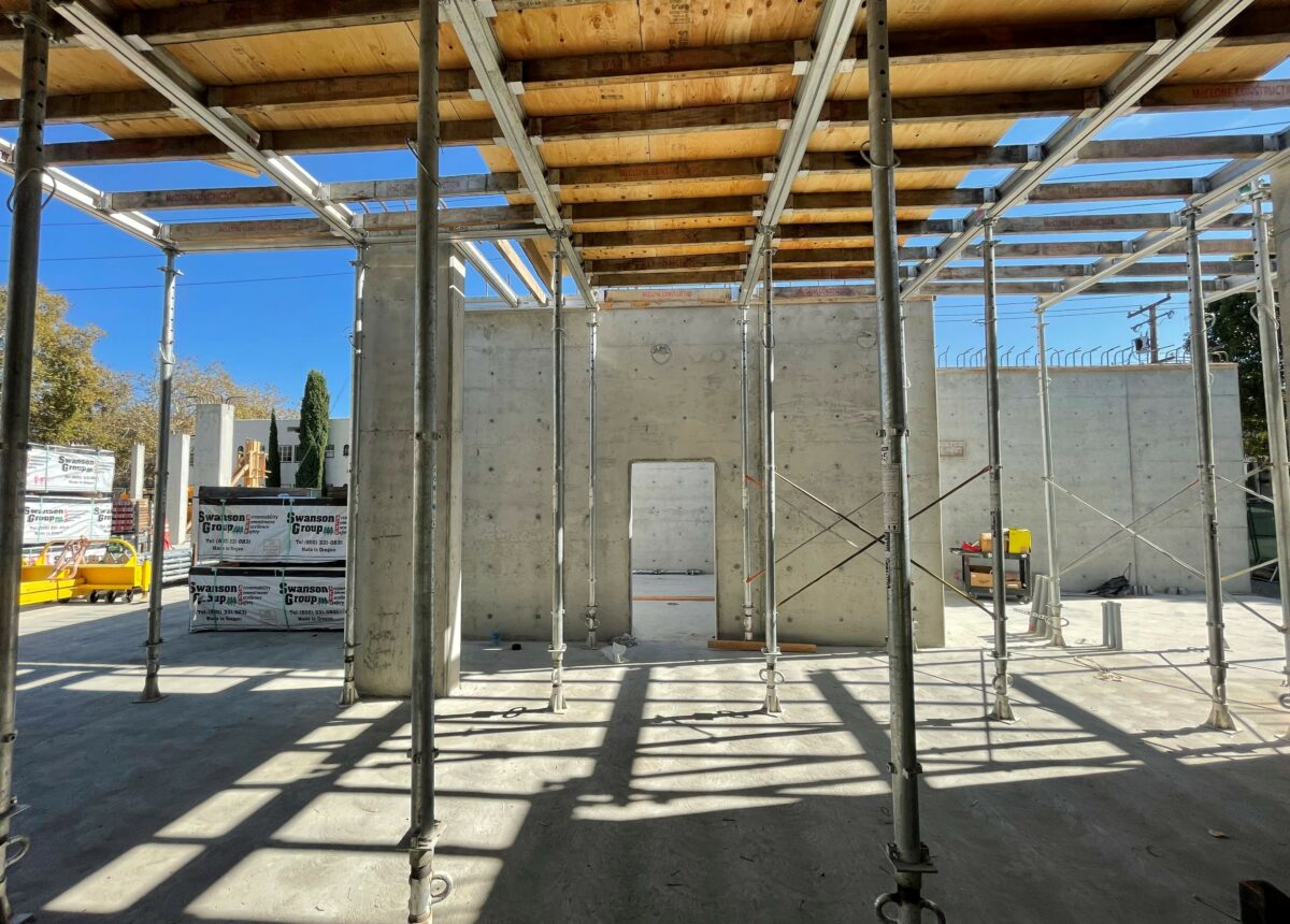 A photo of an construction site with beams and a concrete wall with an open door.