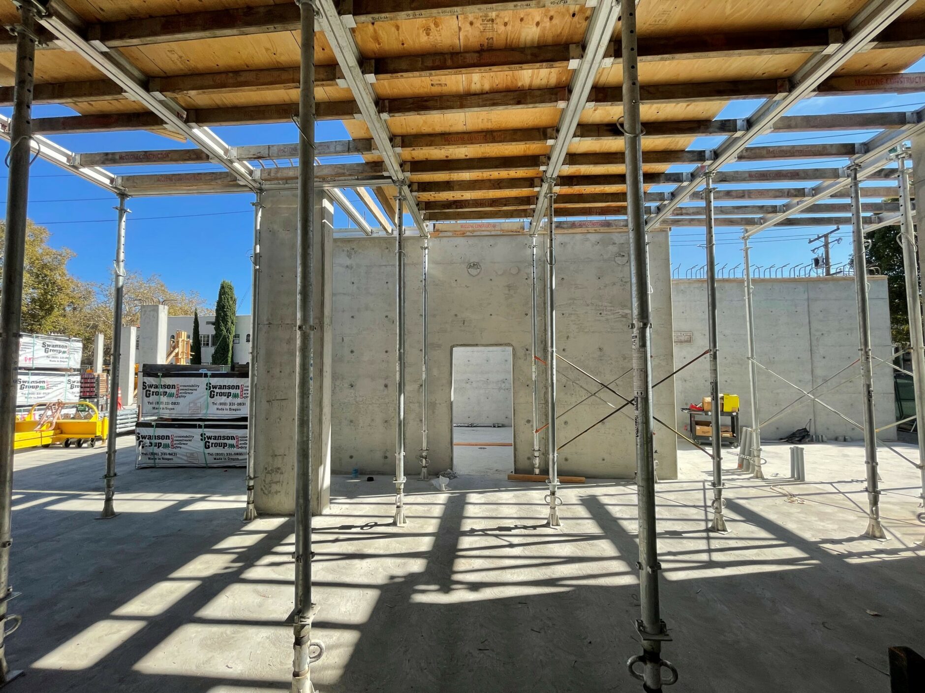 A photo of an construction site with beams and a concrete wall with an open door.