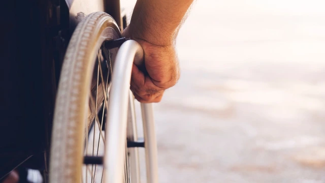 A close up of someone's hand on the wheel of a wheelchair.