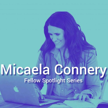 Image of Micaela Connery, a light skinned woman with dark hair, working on a laptop, in a duo pop filter. Text on image reads "Micaela Connery: Fellow Spotlight Series."