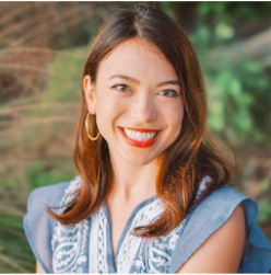 Jennifer Angarita, a light skinned person with auburn hair, is pictured. She is wearing a blue shirt with a white pattern on it.