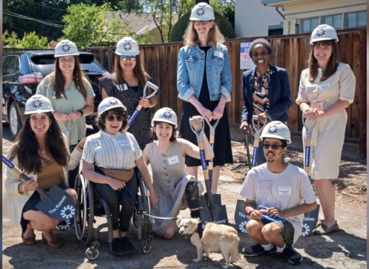 The Kelsey team is pictured in front of a fence, some wearing hard hats and holding shovels