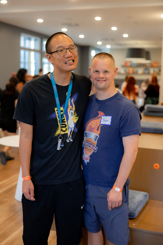 Two residents of The Kelsey Ayer Station pose shoulder to shoulder and smile. 