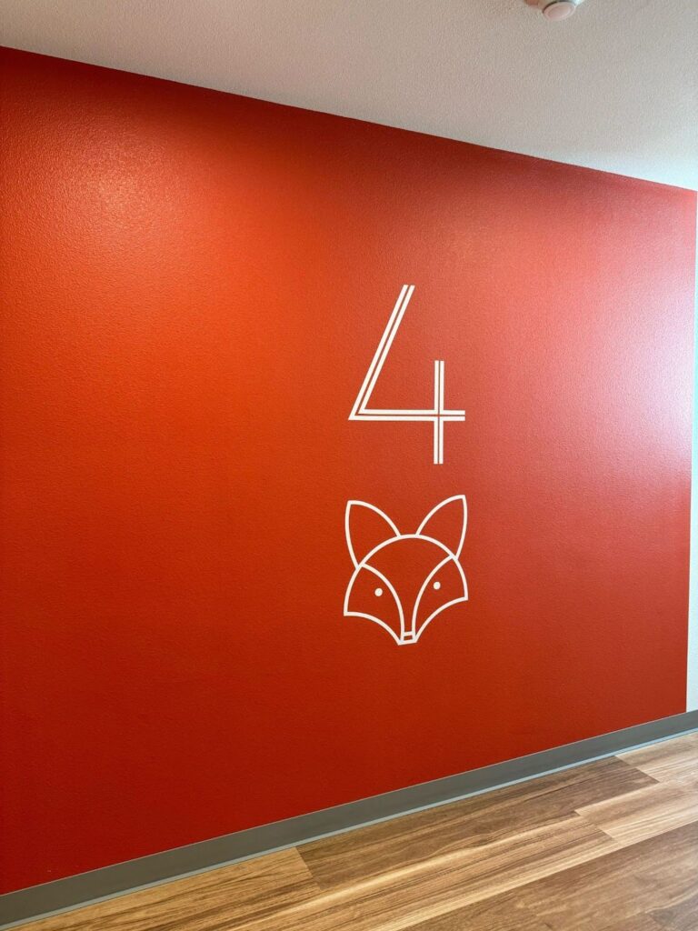 An orange wall with a fox illustration, marking level four of the building. 