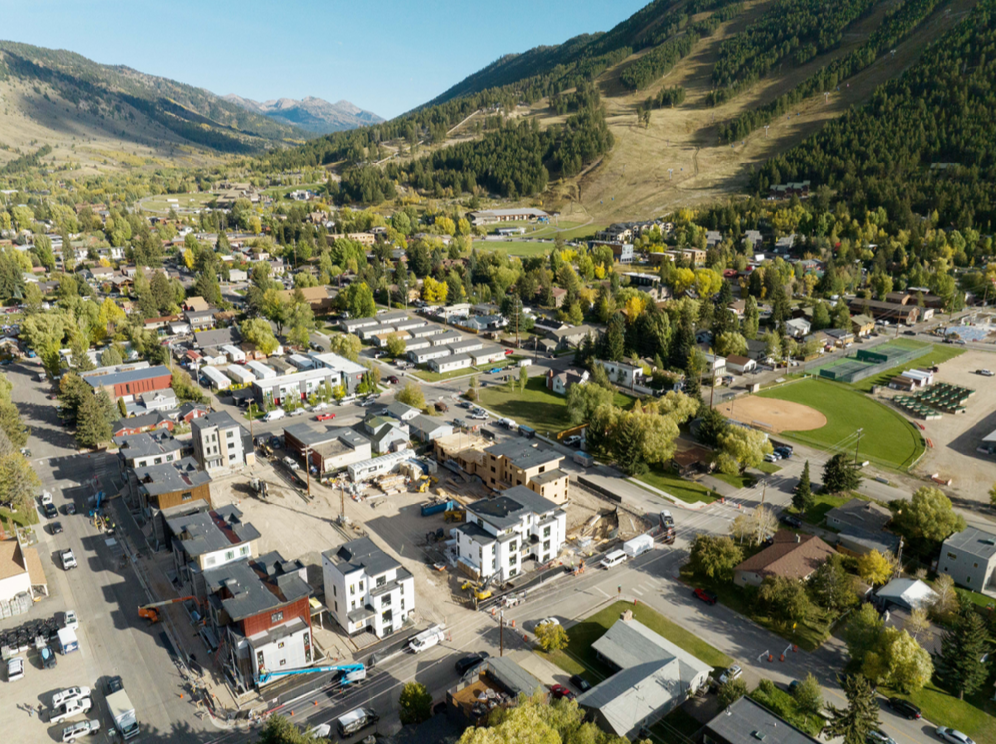 An areal view of a community with homes and businesses. Green mountains surround the community.