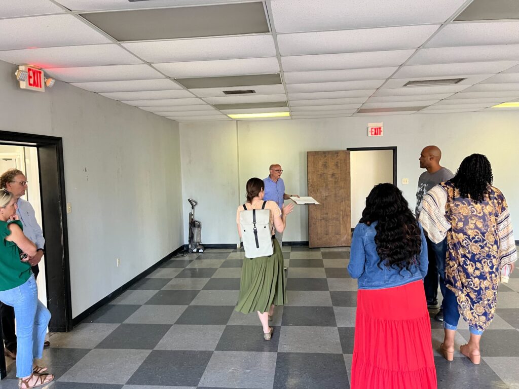 A person holding a large clipboard leads a group of people on a tour of a building.