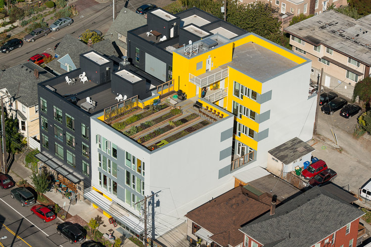 A bird’s eye view of the exterior of Capital Hill Urban Cohousing. A black, white, and yellow apartment building.
