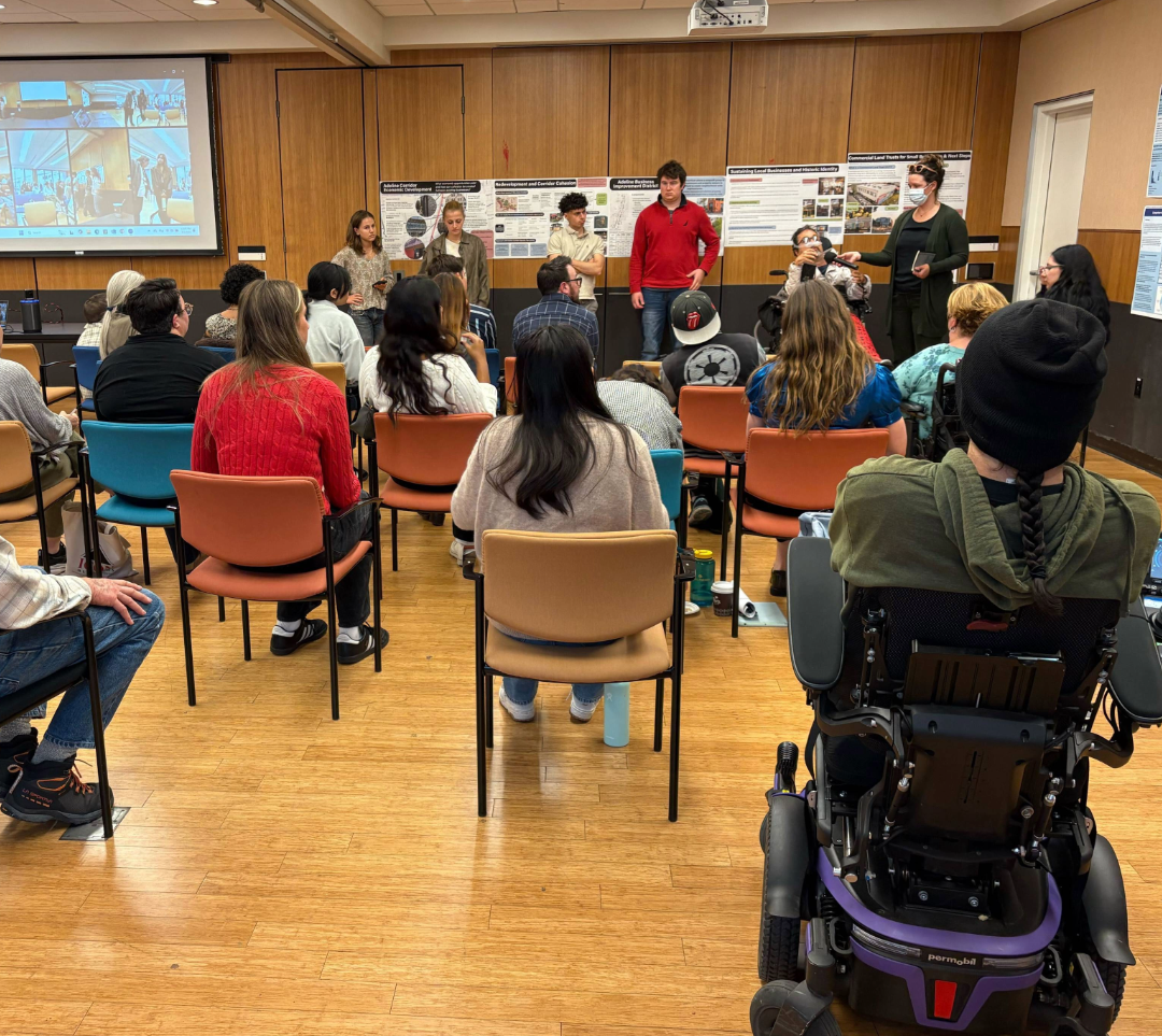 People with and without disabilities present a project to a conference room of people with and without disabilities.