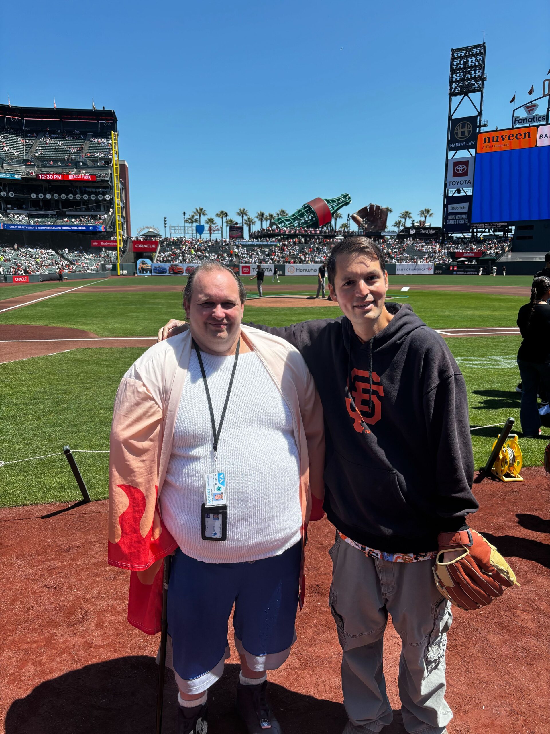 Two residents pose on the San Francisco Giants baseball field. One resident is wearing a baseball glove.