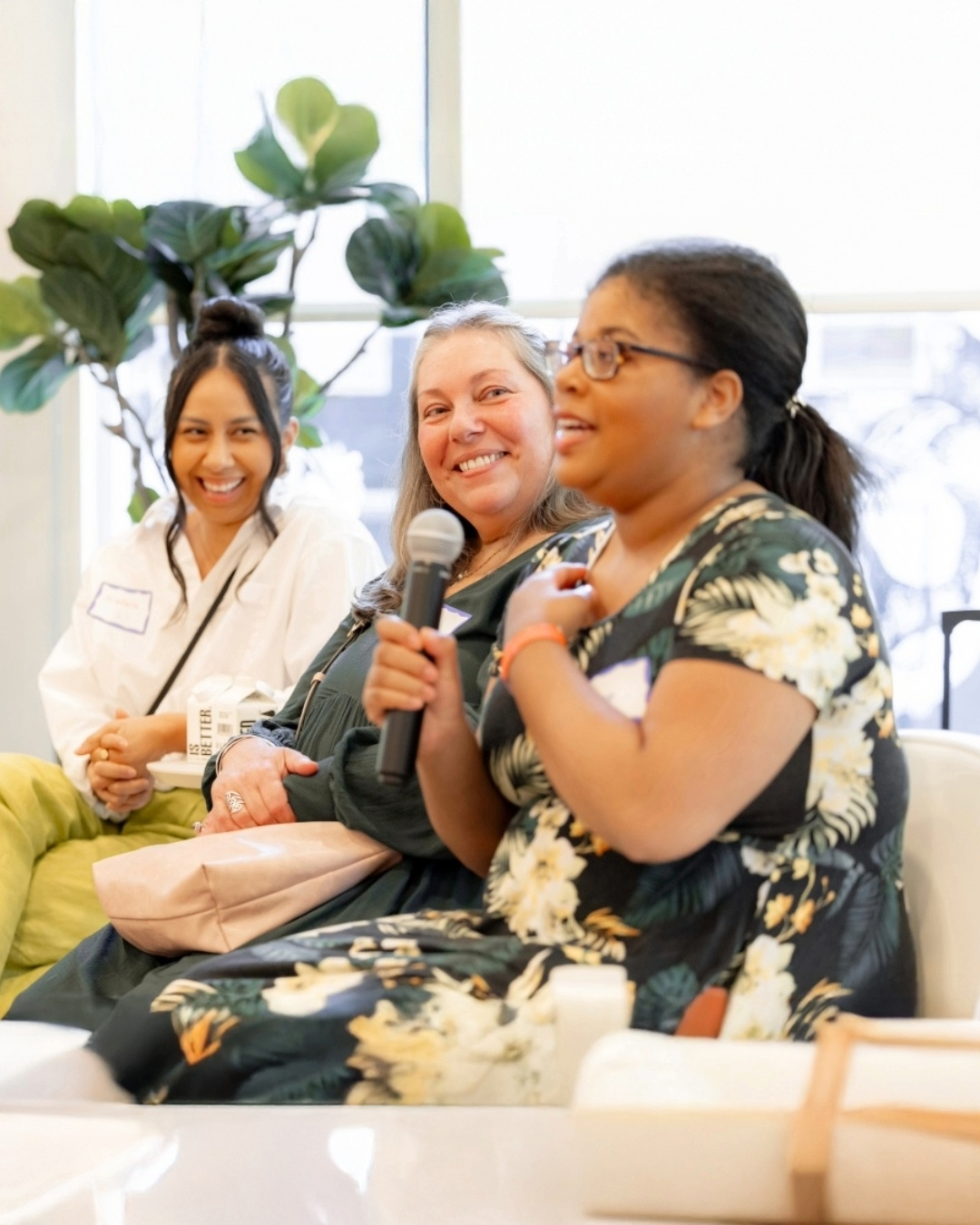 A joyful pictute of three women sittting on a panel at The Kelsey Ayer Station Housewarming. One woman holds a microphone while speaking and the other two look at her and smile.