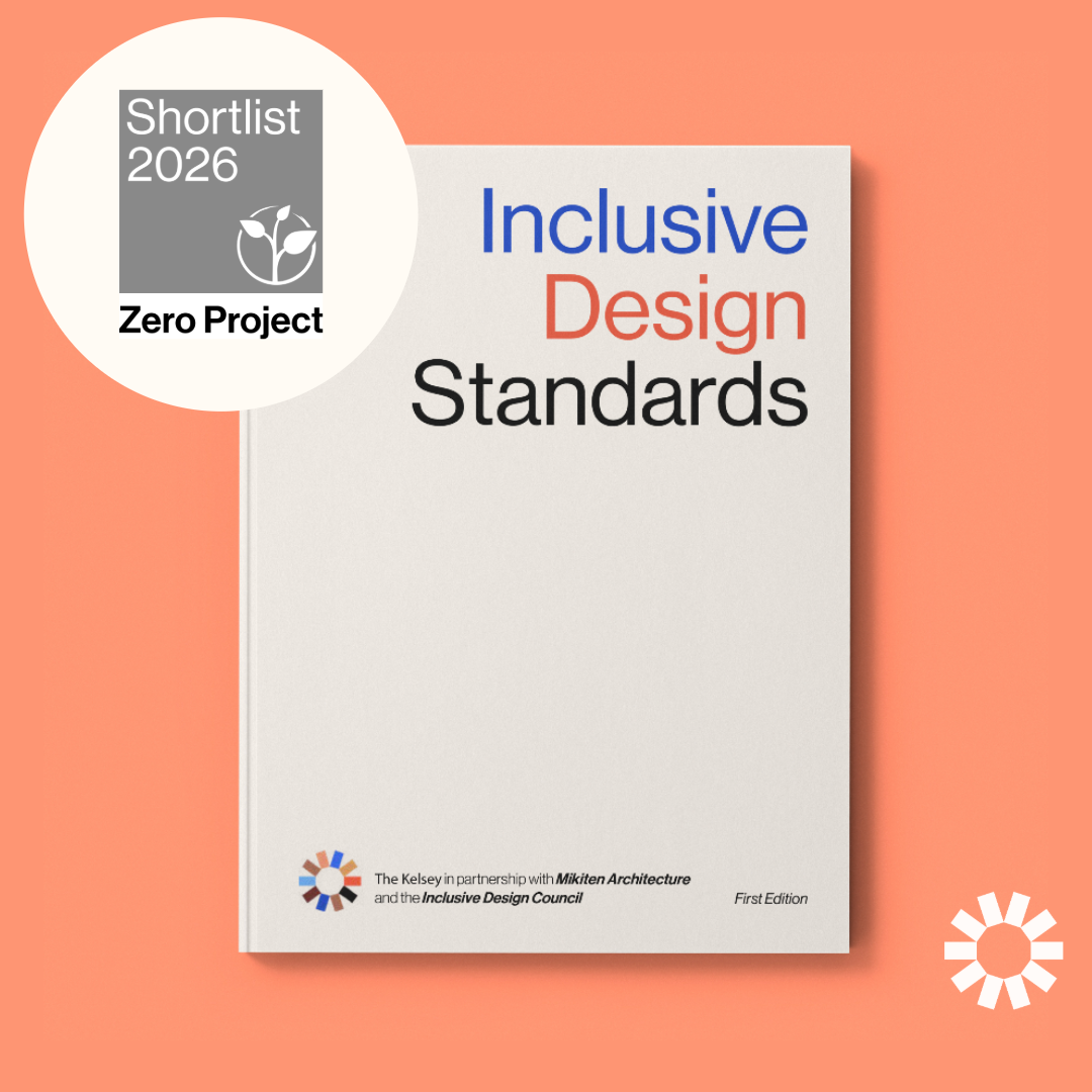 A graphic announcing the shortlisting of the Inclusive Design Standards for the Zero Project Awards 2026. On the left, a white circular badge with a gray square in the center reads: “Shortlist 2026, Zero Project” with the Zero Project logo. On the right, a white book cover is shown against a coral background. The book title reads “Inclusive Design Standards” in blue, coral, and black text. At the bottom, logos and text note that the publication is by The Kelsey in partnership with Mikiten Architecture and the Inclusive Design Council.
