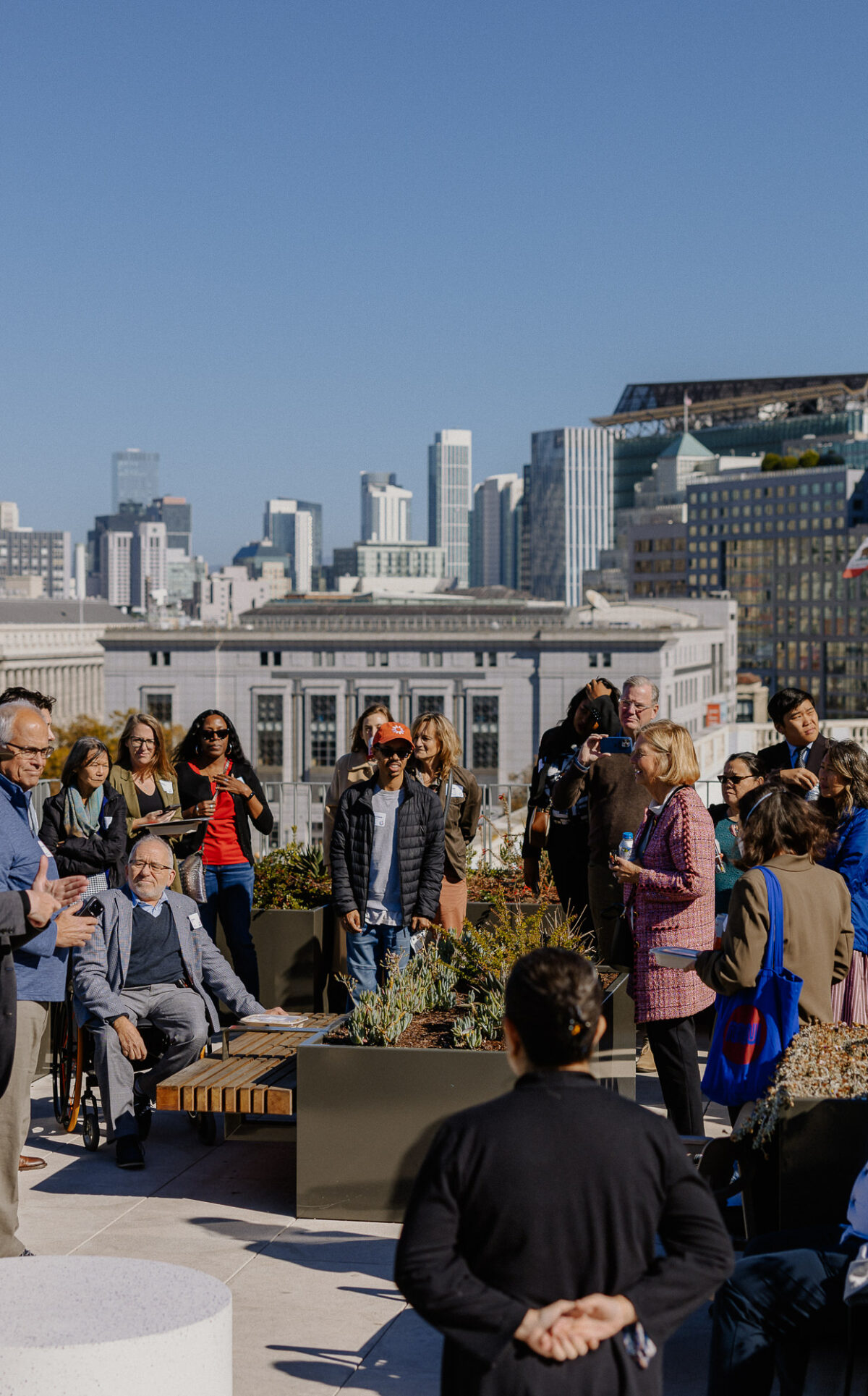 A group of people on a city rooftop terrace with the San Francisco skyline in the back