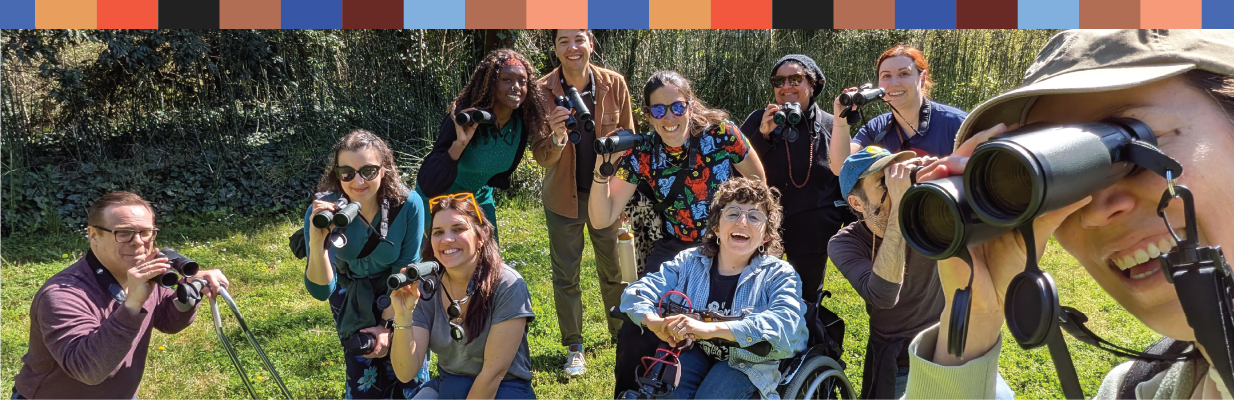 A group of people smiling while looking through binoculars.